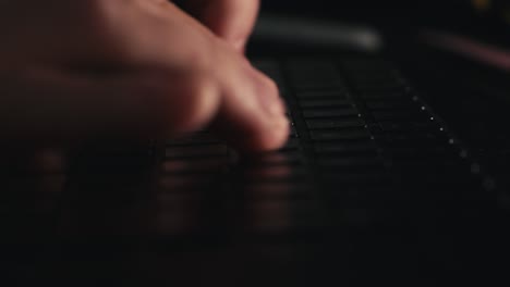 side close up macro shot of a person typing on a black keyboard in a dimly lit room