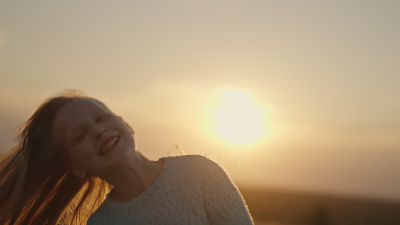 그 소녀는 머리를 흔들고 햇빛 아래에서 긴 머리를 가지고 논다