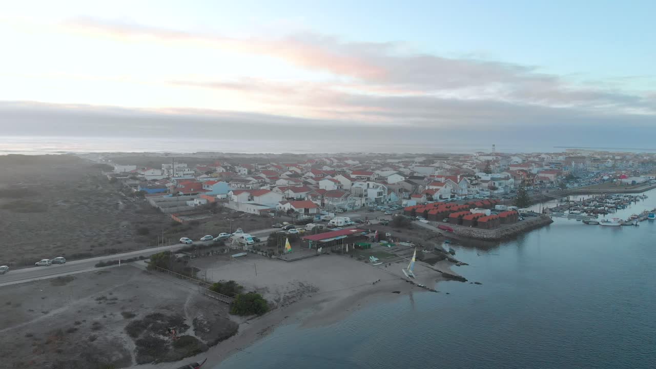 vista aérea durante la puesta de sol de un pequeño pueblo entre el océano y el río