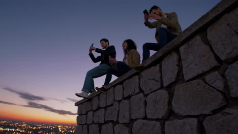 friends capturing panoramic city views at dusk with smartphones