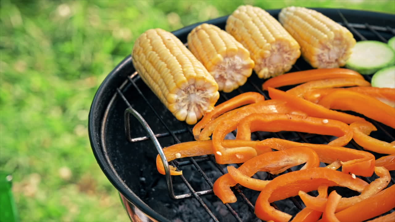 Frying vegetables on a grill at glamping. Corn cobs, bell peppers, onions, zucchinis