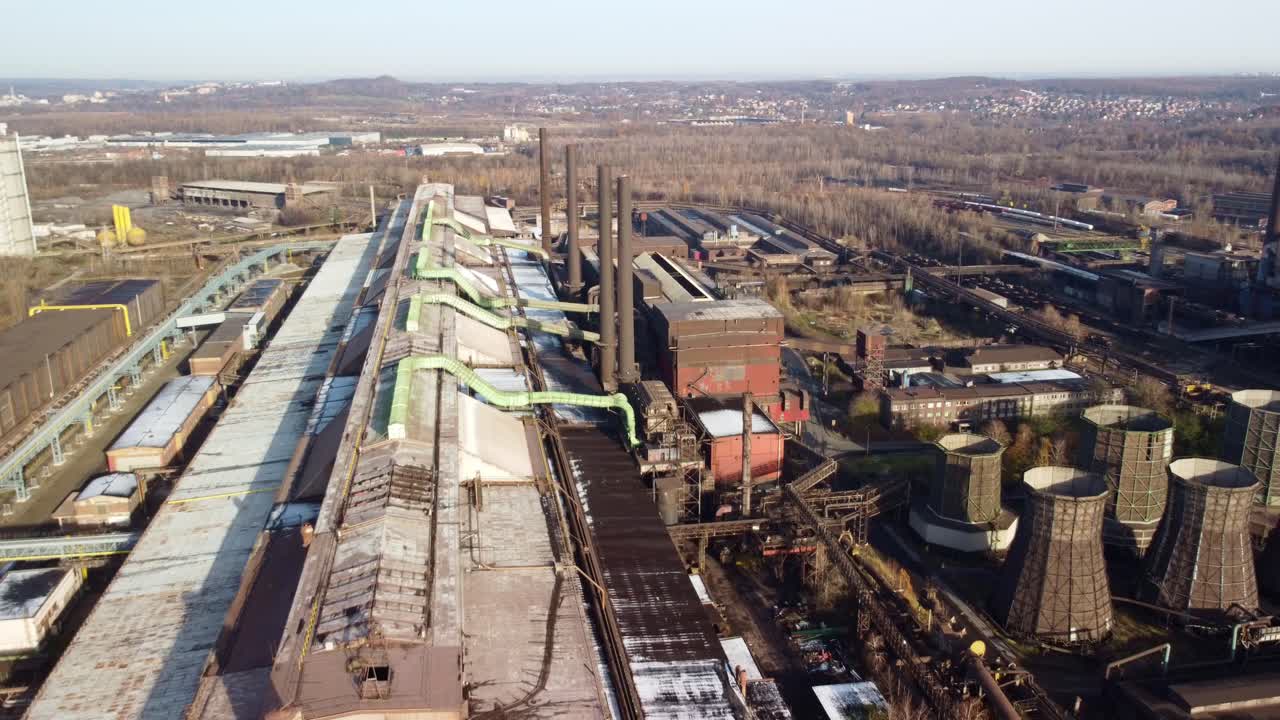 воздушный снимок большого промышленного комплекса с дымоходами и охлаждающими башнями, окруженного зеленью