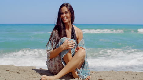 Mujer-Atractiva-Sonriente-Sentada-En-La-Arena-De-La-Playa