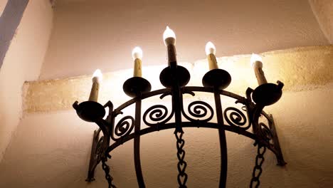 Slow-dolly-shot-of-a-metallic-candle-holder-burning-candles-in-a-chateau