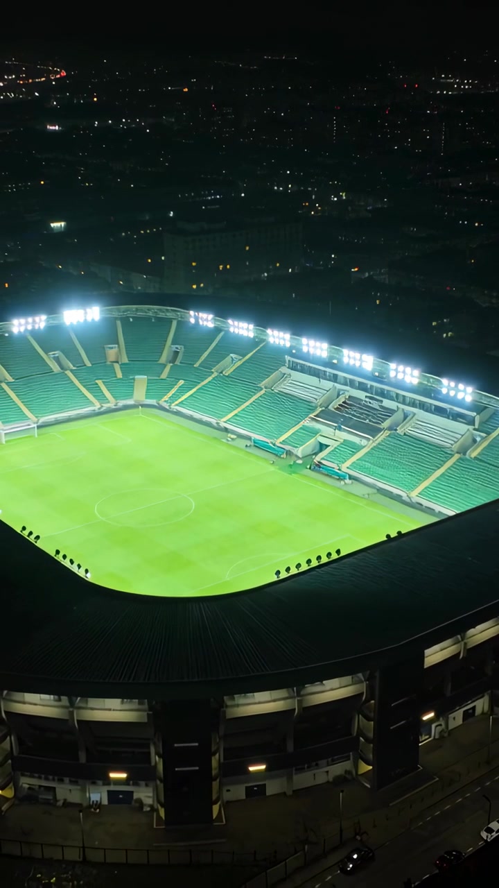 Video verticale: Telecamera che si inclina rivelando uno stadio illuminato di notte per mostrare il campo vuoto e le luci.