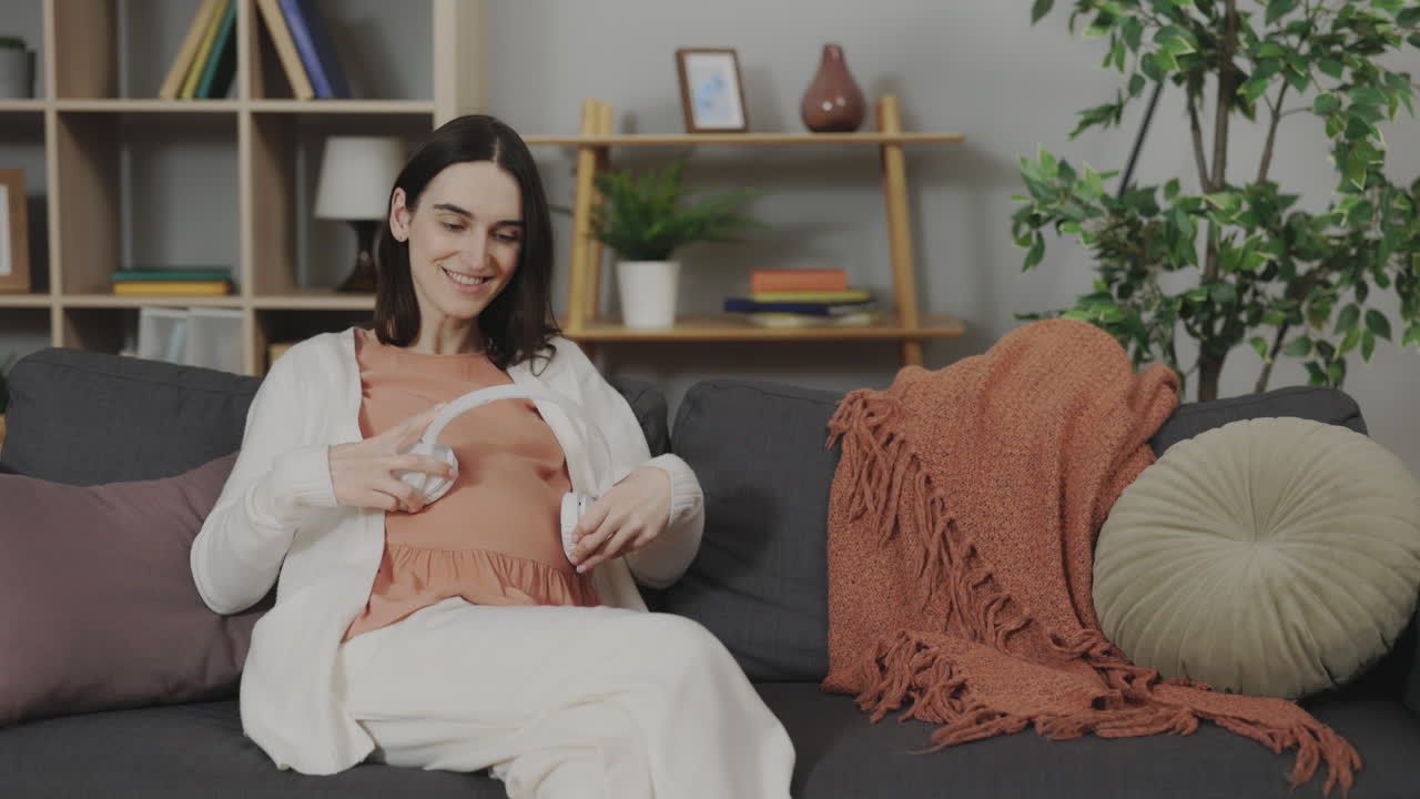 Pregnant Woman Listening to Music on Headphones at Home
