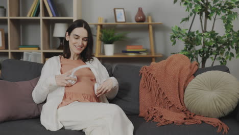 pregnant woman listening to music on headphones at home