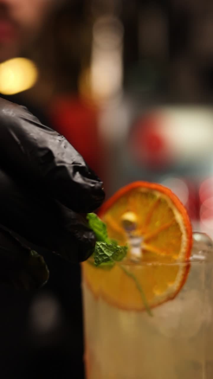 Bartender preparando um coquetel com fatia de laranja e hortelã