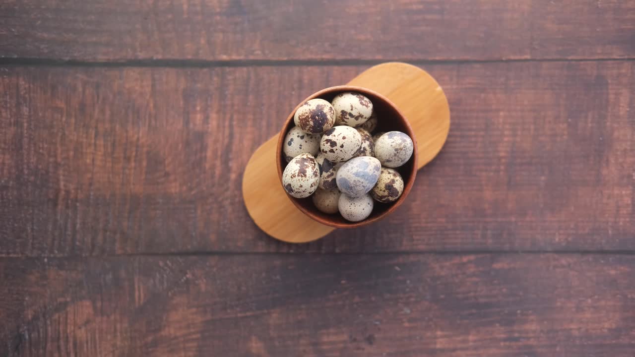 recogiendo a mano huevos de codorniz de un cuenco de madera