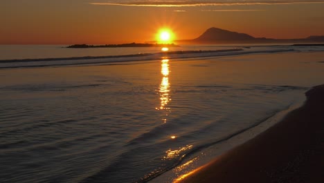 Sol-Naciente-Que-Se-Refleja-En-Las-Olas-Poco-Profundas-Del-Océano,-Amanecer-En-La-Playa-Del-Mar-En-Calma,-Mediterráneo,-España