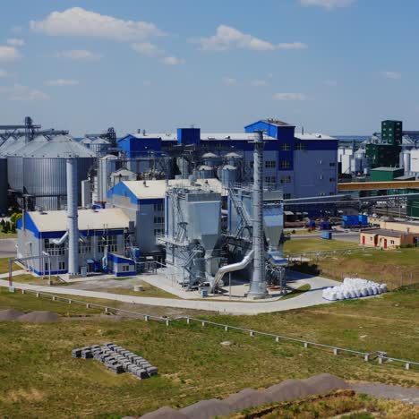 Contemporary factory on field. Granary elevator in summer. Silver silos on agro-processing and manufacturing plant for storage of agricultural products.