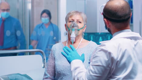 doctor in mask helping old lady to breathe