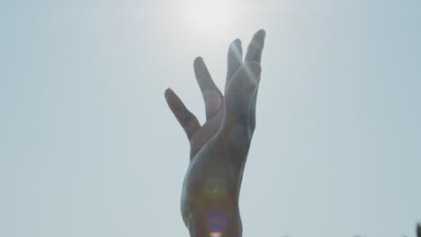 la mano de un hombre negro en el aire contra los brillantes rayos del sol
