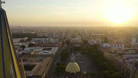 drone flies between guadalajara cathedral spires during dramatic morning sunrise