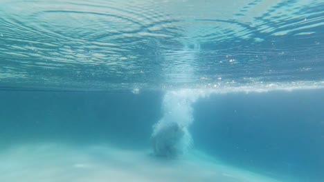 Joven-Saltando-A-La-Piscina-Azul-Causando-Muchas-Burbujas,-Florida