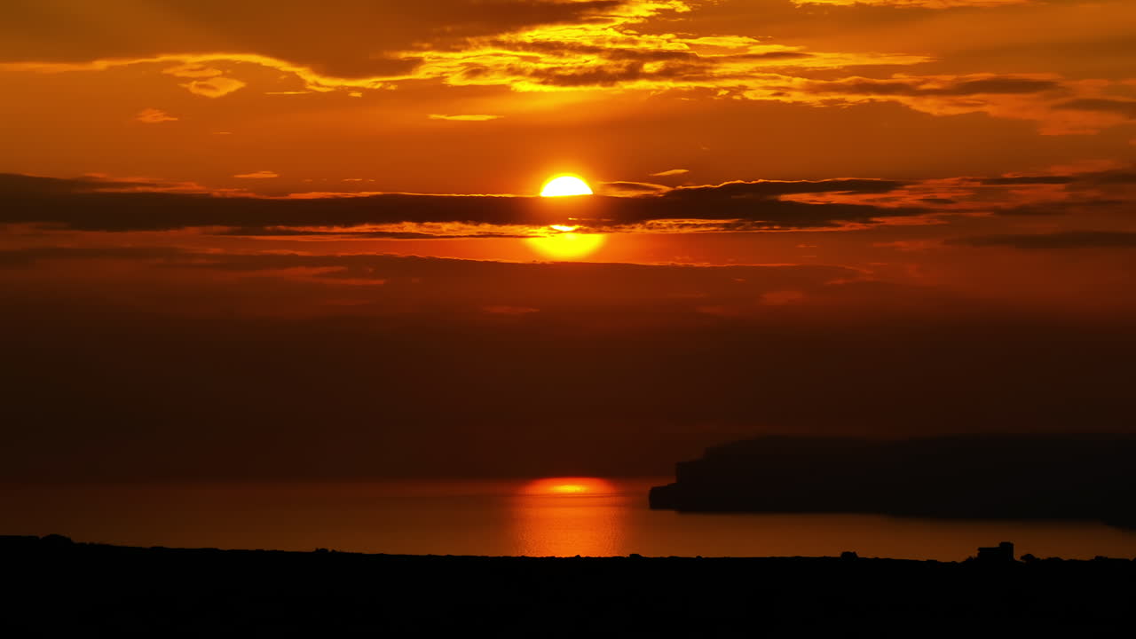 Ilta-aurinko osittain dramaattisten auringonlaskun pilvien peitossa Maltalla – teleobjektiivilla otettu dronekuva.