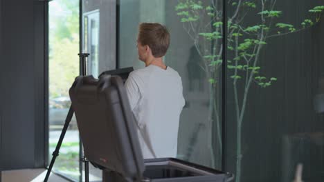 técnico masculino de plano de planta camina hacia el trípode para colocar el dispositivo de matterport