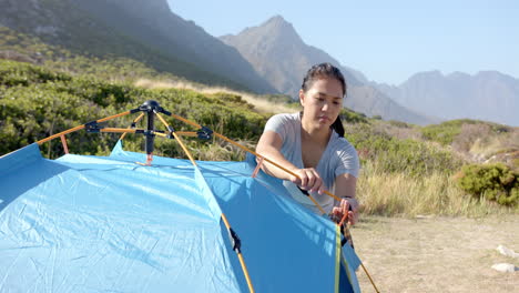 setting up tent, woman camping in mountains during outdoor adventure