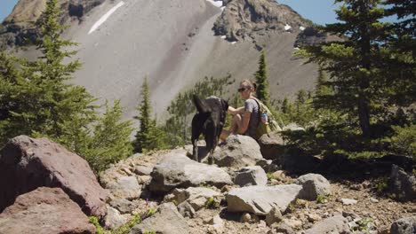 Girl-and-black-lab-taking-a-break-on-mountain-hike