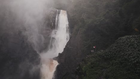 people at the edge of a cliff with salto de bordones in isnos, huila, colombia