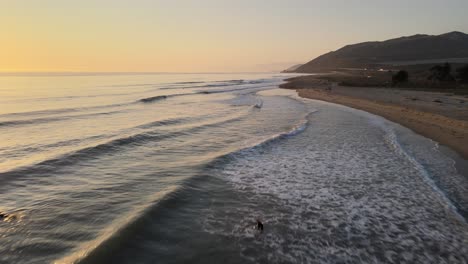 a drone shot skimming over the surf and waves near the beach