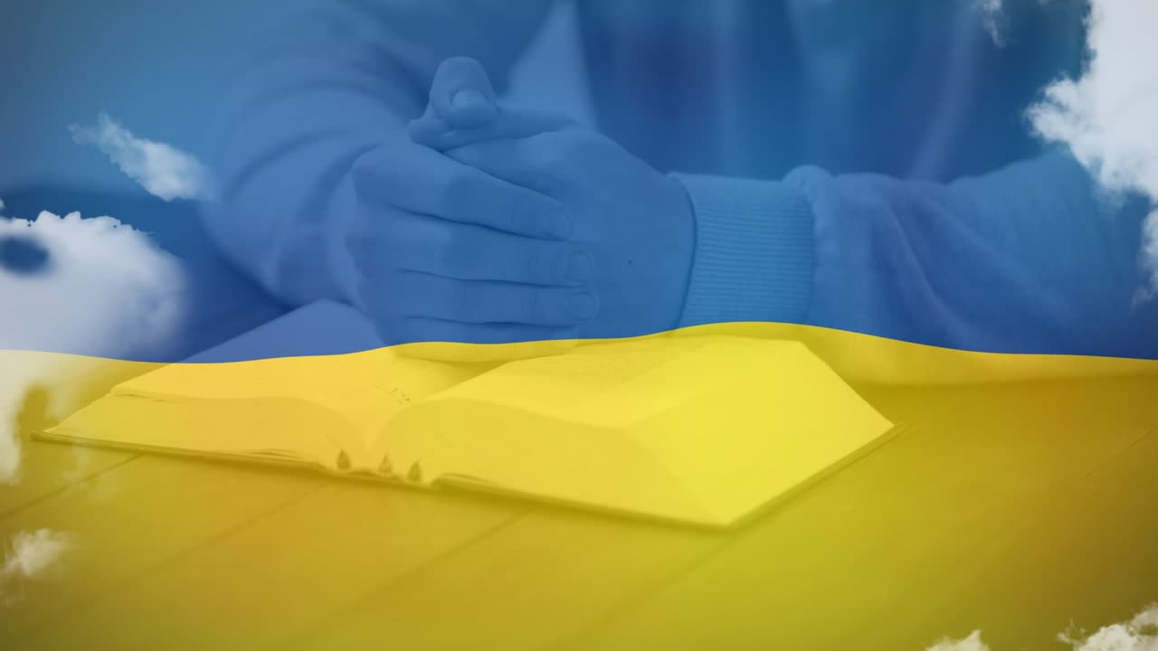 Mani che poggiano su un libro con bandiera ucraina e nuvole, creando un effetto animazione
