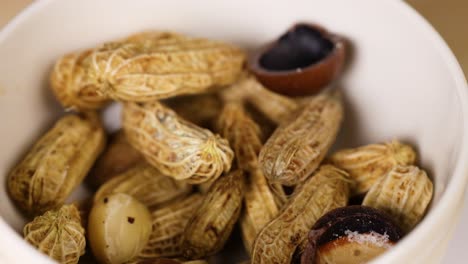 peanuts and nuts arranged in a white bowl