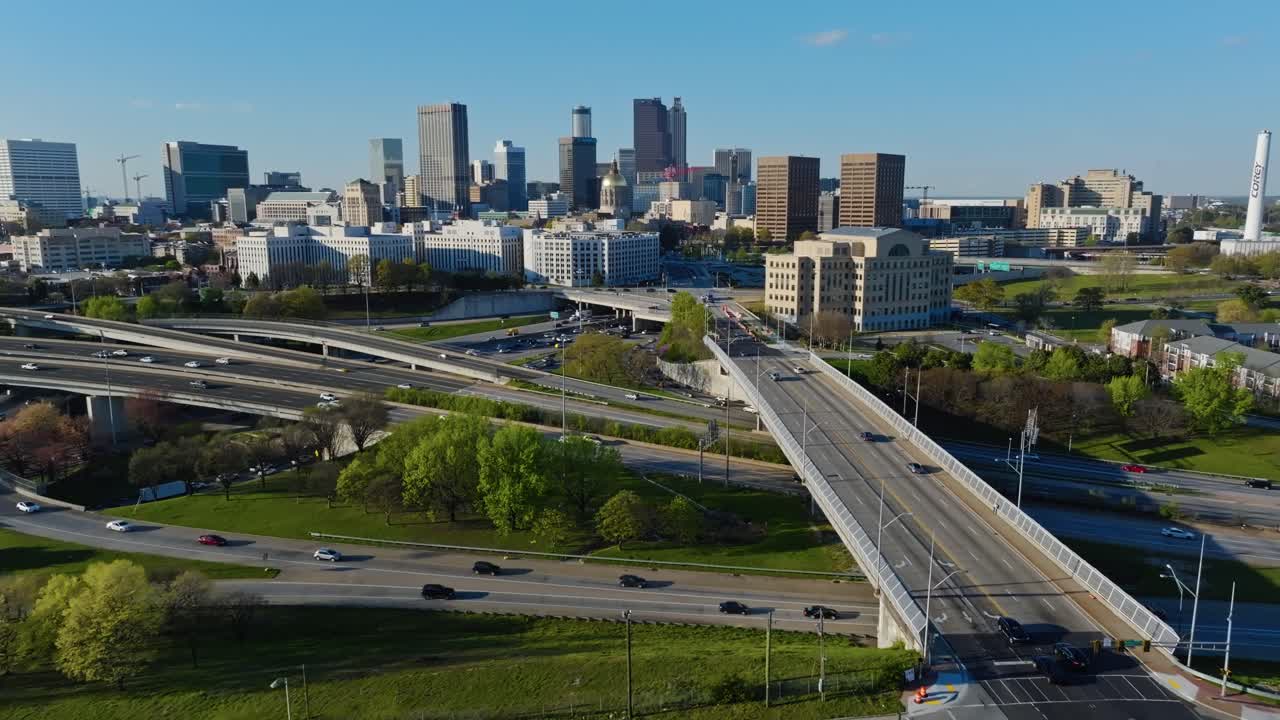Intersection highway in front of skyline of Atlanta, Georgia. Sunset time in american metropolis. Aerial establishing wide shot. Modern skyscraper and office buildings.