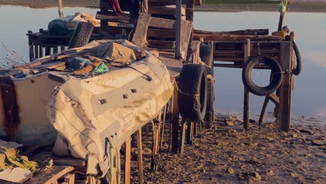 Szene-Aus-Altem-Müll-Und-Abgenutzter-Promenadenstruktur-In-Der-Nähe-Der-Flusswasseroberfläche,-Aufnahme-Des-Sonnenlichts-Aus-Niedrigem-Winkel-Am-Tag