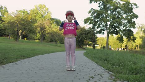 young cute child girl in sportswear making fitness exercises outdoors in park. workout for kids