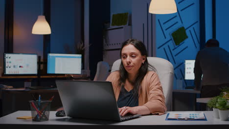 exhausted workaholic businesswoman analyzing financial graphics on laptop