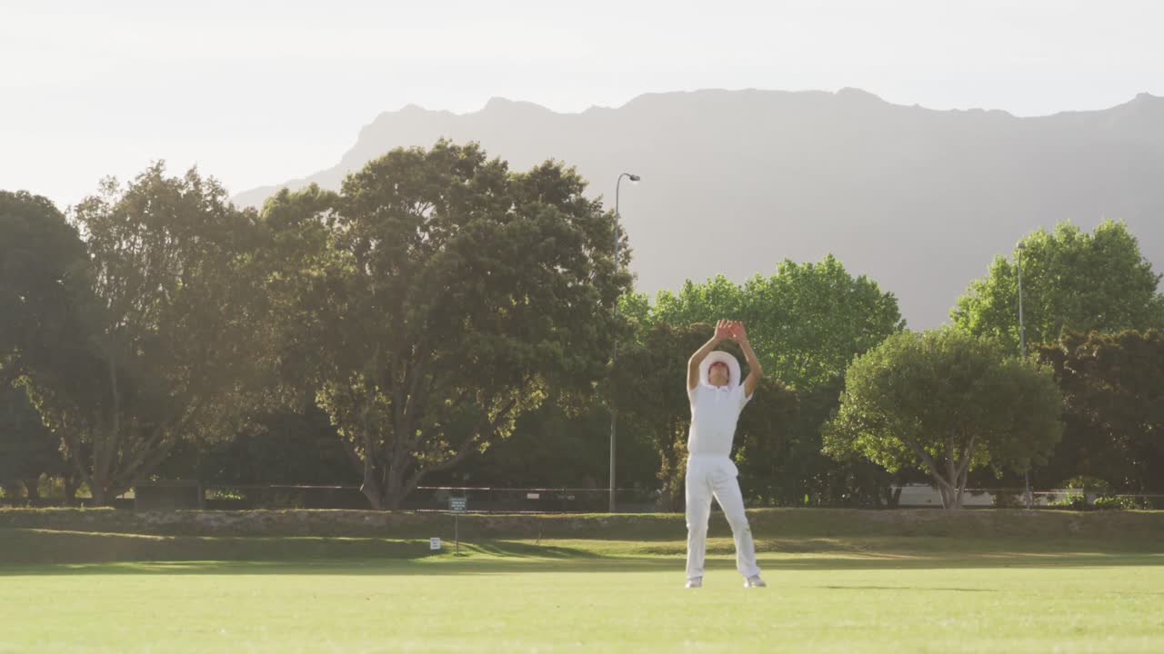 크리켓 선수 가 피치 에서 공 을 잡고 있다