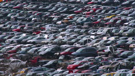 cars sit in rows in a junkyard in the snow 2