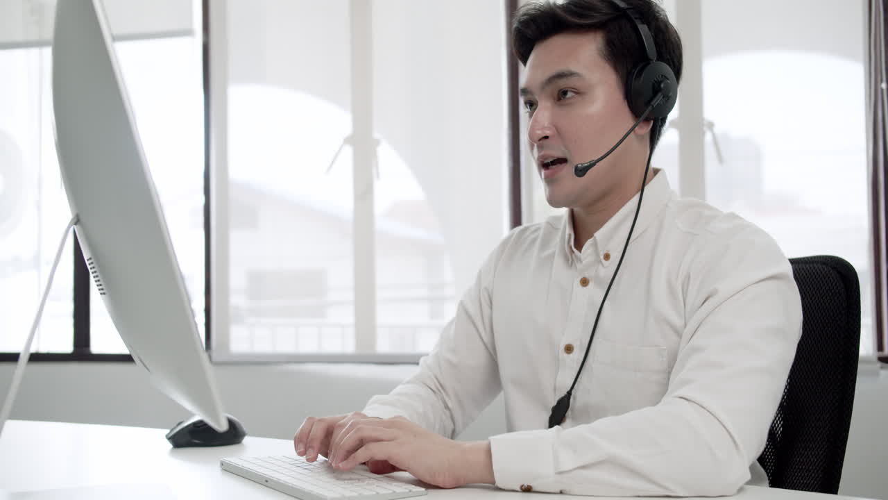 Typing using his keyboard, a call center agent attends to his clients online.