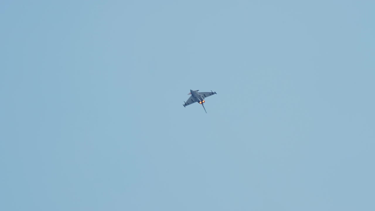 Fighter jet banking with afterburners glowing