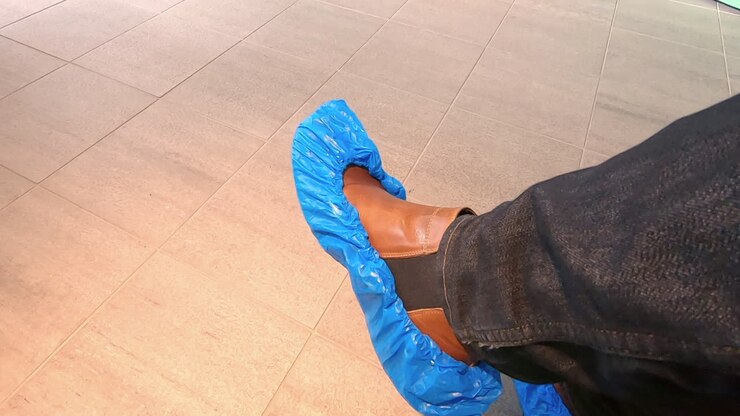 Uomo annoiato seduto in attesa con copriscarpe ai piedi