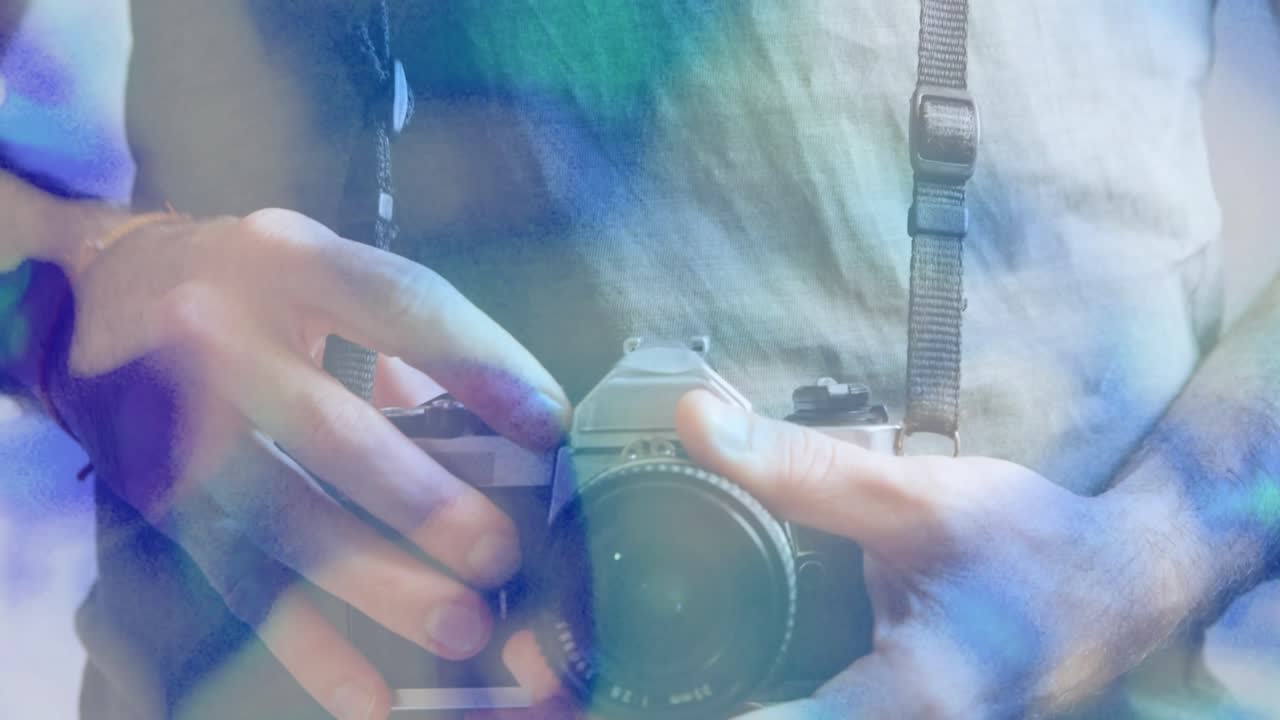 フレアの中でカメラストラップを振り、ビンテージのフィルムカメラを手に撮影の準備をするフォトグラファー。