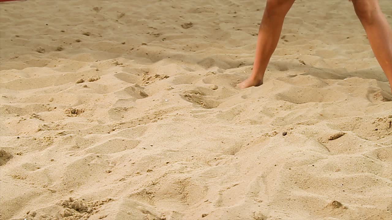 해변 배구 선수 가 모래 에 무 을 고 있다