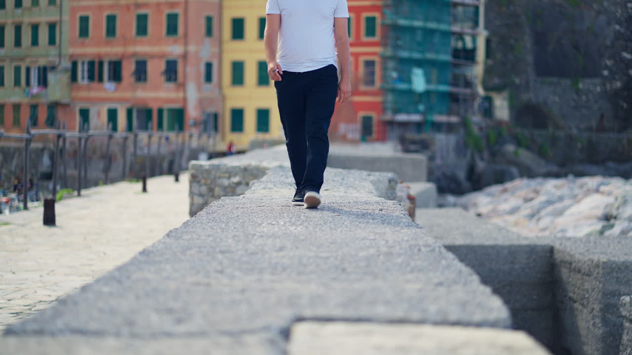 Persona che cammina sul lungomare di Camogli, in Italia, con edifici colorati sullo sfondo