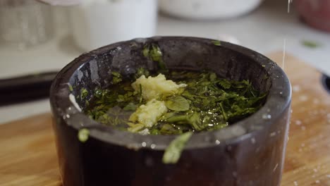 adding olive oil into a bowl with garlic and herbs