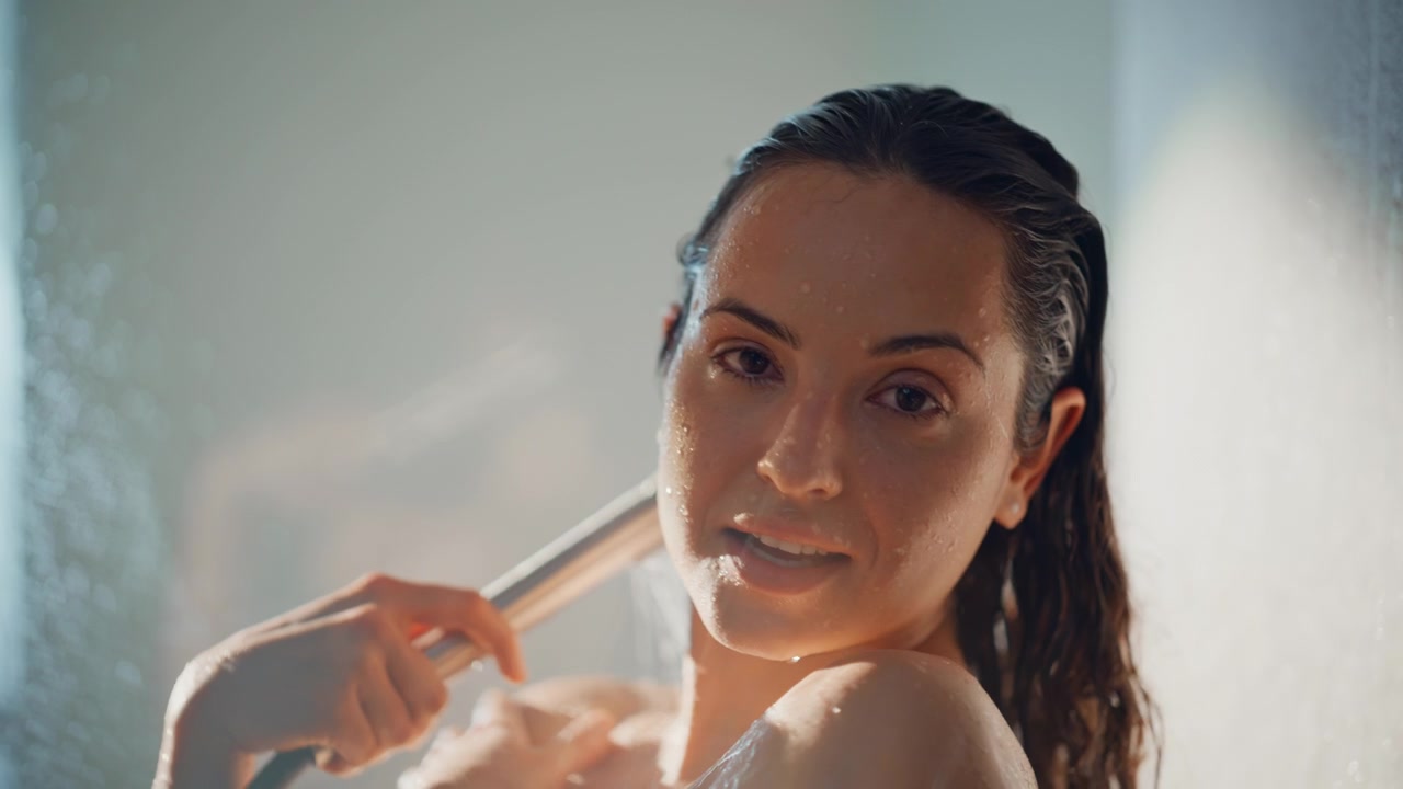 Donna che si sciacqua il viso sotto la doccetta. Primo piano di benessere e spa.