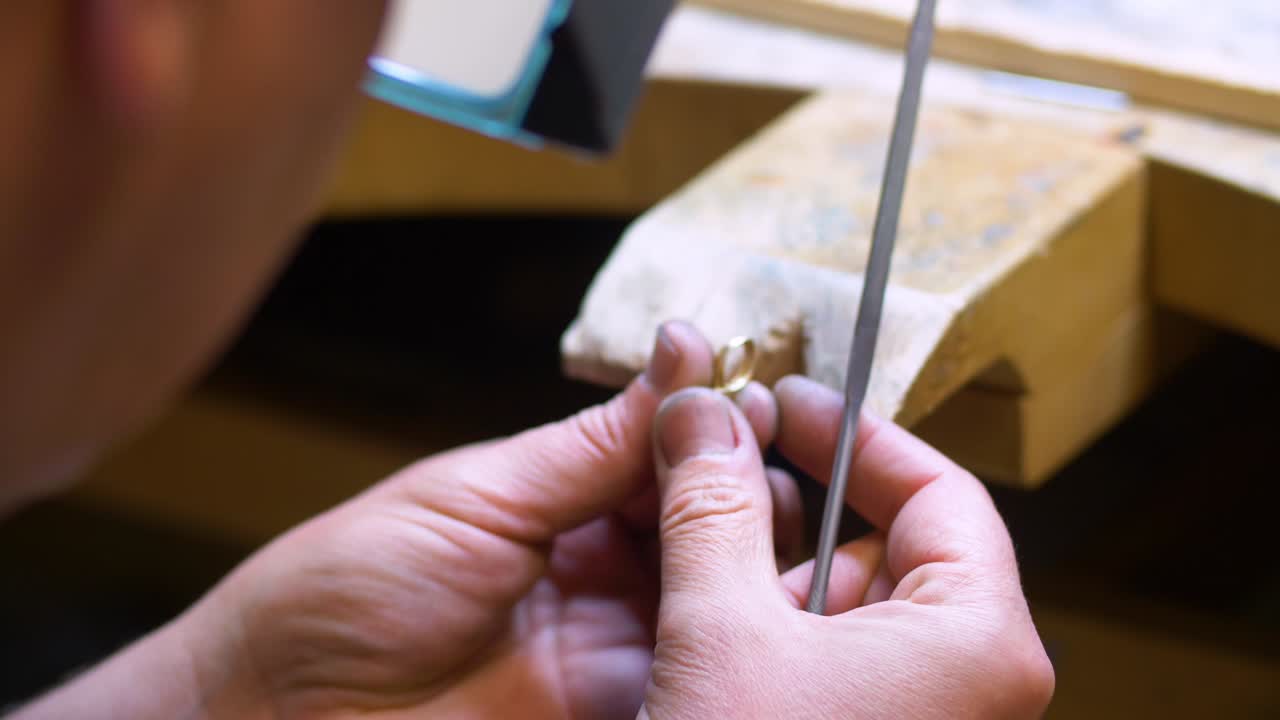 Male jewelry maker hand filing a piece of jewellery in a workshop