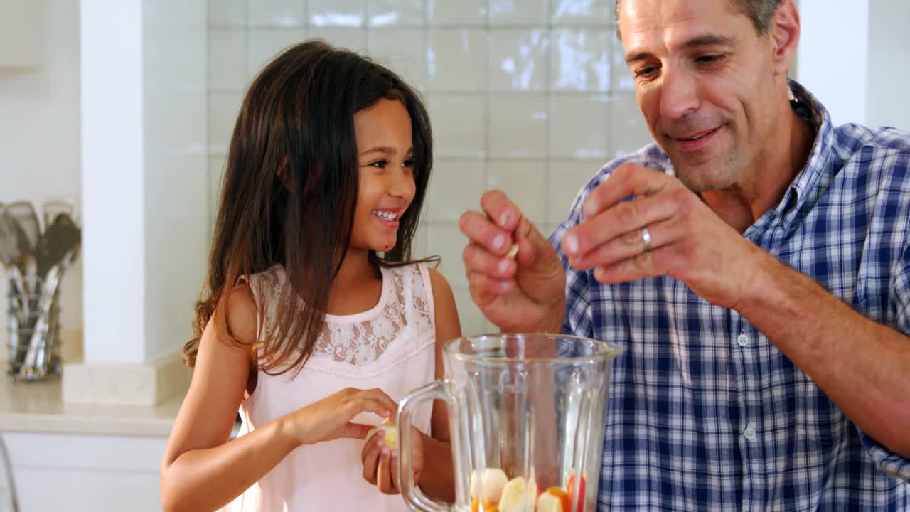 Padre e hija preparando batidos en la cocina