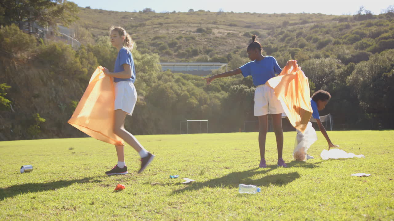 Picking up trash, girls participating in outdoor school cleanup activity