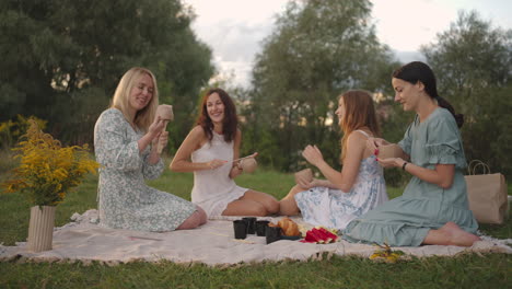 Young-women-in-nature-in-the-field-in-the-park-together-sculpt-with-tools-tap-clay-products-with-shovels.-Girls-communicate-share-their-impressions-laugh.