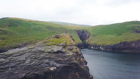 Aerial:-arc-shot-of-clifftop-Hikers-on-British-coastline,-overcast-day