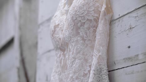 close up of a gorgeous wedding gown hanging on a white wood wall