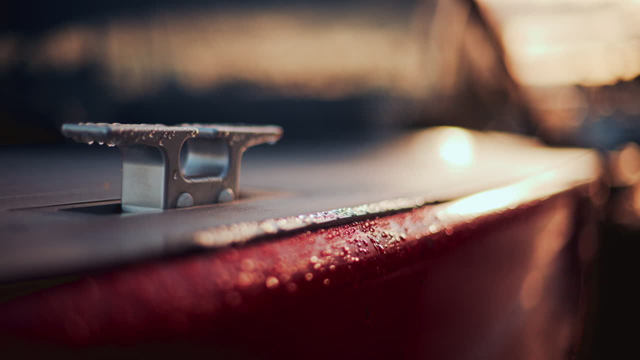Close up of a boat cleat on a red hull, shining under warm evening sunlight