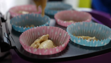 adding cake mixture to paper cupcakes trays for baking