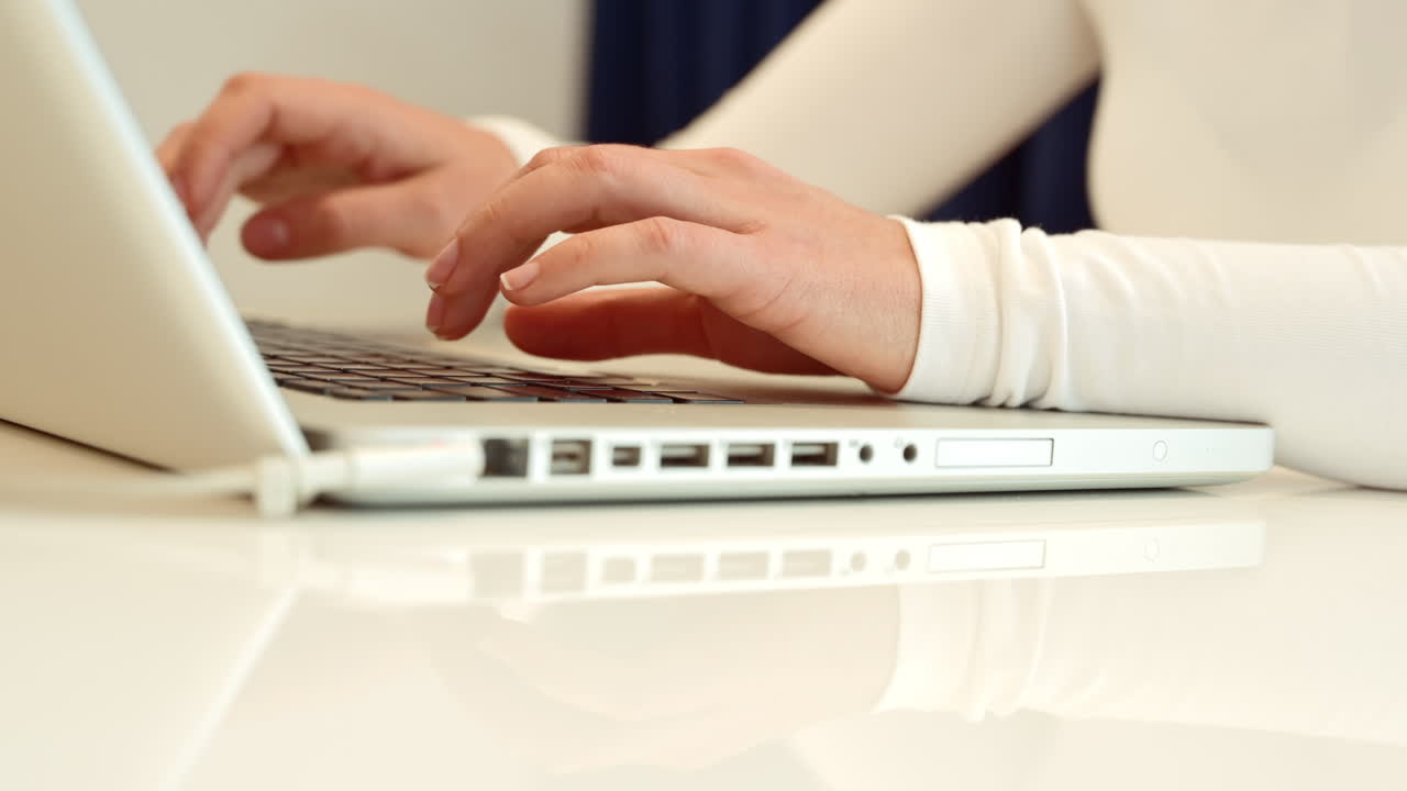 Woman wearing white clothes working on notebook at home, close up
